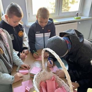 Dzieci piszą dobre słowa do koszyczka 