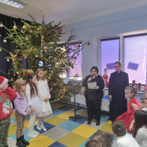 Nauczyciela i ksiądz proboszcz wręczają dyplomy i nagrody 