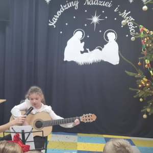 Uczennica klasy II gra na gitarze kolędę